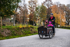 Bygga och bo i Ulricehamn - En pappa som cyklar med sina två barn som sitter i en cykelkärra